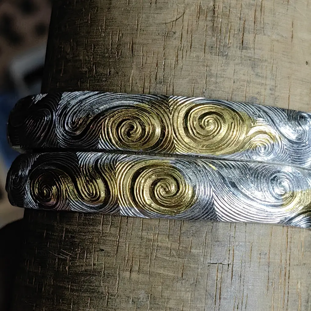 Pair of silver cuffs with developed surface tone and hand-worked spirals
